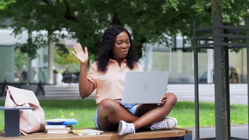 Smiling Woman Using Laptop on Park Bench