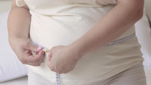 femme enceinte assise sur le lit mesurant le gros ventre d'une femme enceinte avancée le trimestre dernier