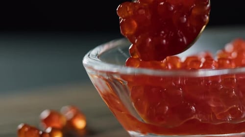 Putting Red Caviar in Glass Bowl Closeup