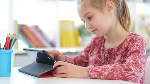 Young Girl Using Tablet at a Desk Indoors