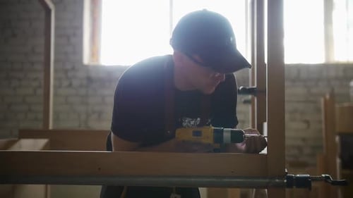 Carpentry Works in Workshop Man Worker Setting Up the Wooden Construction Drilling in the Screws