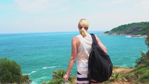 traveler girl looks at a beautiful seascape on the edge of a cliff