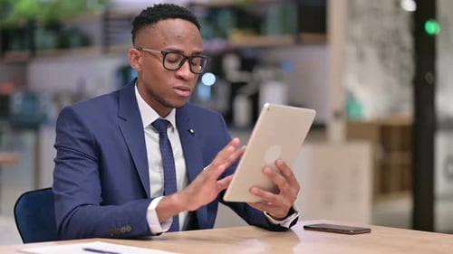 African Businessman Reacting to Loss on Tablet in Office