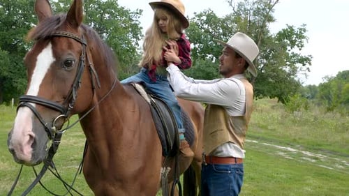 A Young Cowboy Puts His Pretty Daughter on a Horse