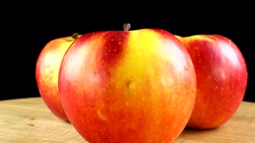 Red and Yellow Apples Rotating on a Wood Surface