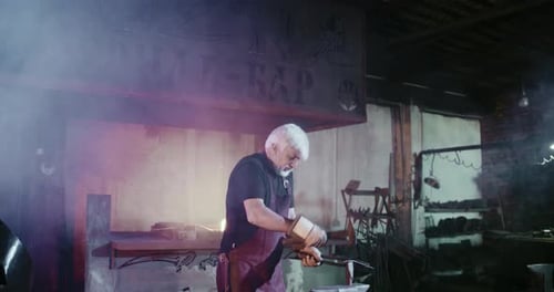 Senior Blacksmith Hammering Metal in a Smoky Workshop