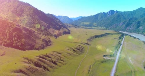 Aerial Rural Mountain Road and Meadow at Sunny Summer Morning. Asphalt Highway and River.