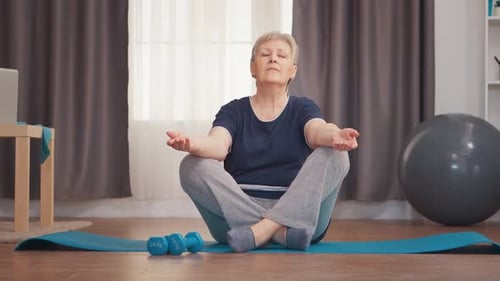 Senior Woman Meditating at Home on Yoga Mat