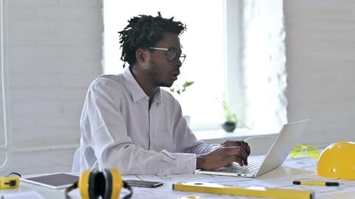 Overwhelmed Man Typing at Desk in Modern Office