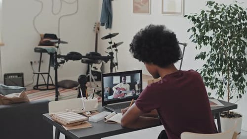 Young Adult Taking Online Guitar Lesson at Home