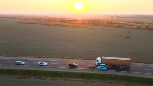 Luftaufnahme eines Sattelschleppers mit Frachtanhänger, der am Abend auf der Autobahn fährt und Güter transportiert
