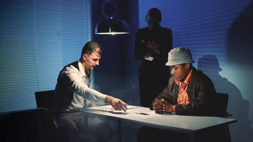 Tense Interrogation with Handcuffed Suspect in Dark Room