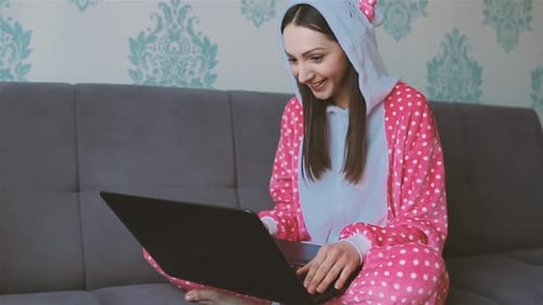 Woman in Pajamas Using Laptop on Couch