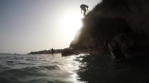 Junge springt von einem Felsen im Strand