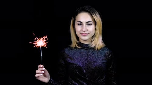 Woman Holding Sparkler Against Black Background