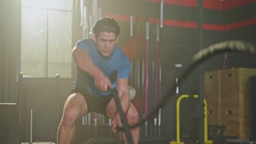 Man Works Out with Battle Ropes in Gym