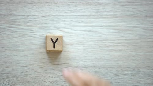 Hand Spells Word 'Yes' with Wooden Blocks