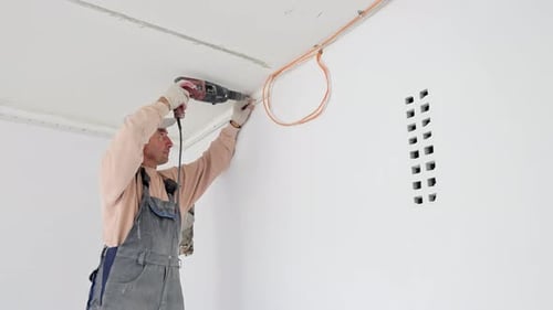 Le maître d'œuvre perce un trou dans le mur pendant les travaux de réparation de la pièce