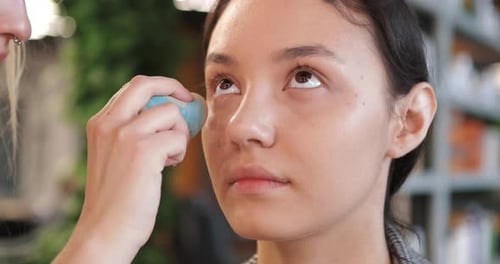 Woman Receives Makeup Application in Bright Studio