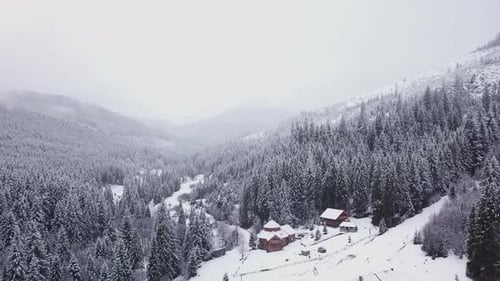 Flug über Wald und ein Dorf in einem Gebirgstal im Winter