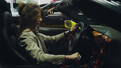 Aufgeregte Dame, die im Salon alle Funktionen des modernen Autos ausprobiert
