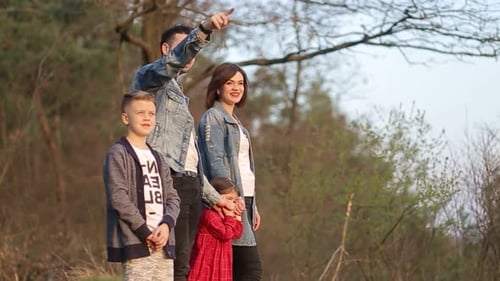 Happy family resting together on green grass in city park.