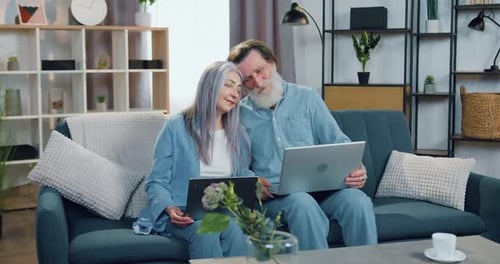 Mature Couple Sharing Laptops on Sofa