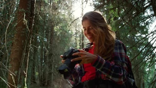 Girl with Photo Camera Standing in Forest