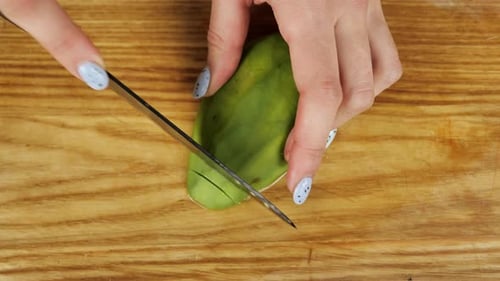 Slicing a Green Avocado on a Wood Board