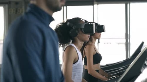 4K Athletic man and woman wearing VR glasses jogging exercise on treadmill at fitness gym.