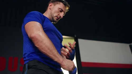4K Caucasian man wrapping hands with boxing wraps while do boxing exercise at gym.