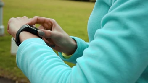 Woman Runner Using Smart Watch Fitness Tracker in Park