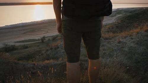 Fotógrafo irreconocible con mochila y trípode está de pie en la colina y disfrutando