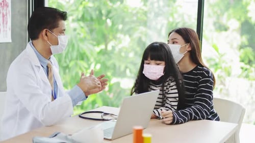 Doctor Speaking with Child and Mother in Office
