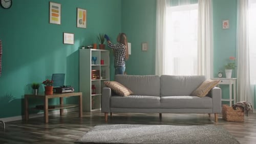 Woman Dusting Plants in Sunny Teal Living Room