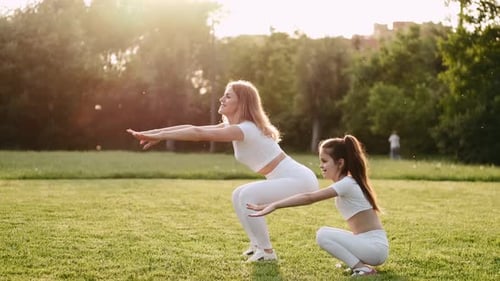 Woman and Child Performing Squats in Grassy Area