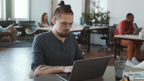 Caucasian Man Working on Laptop in Open Space Office