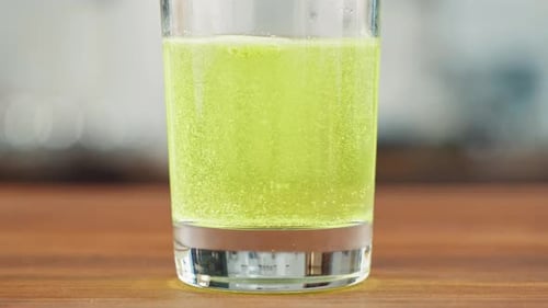 Effervescent Green Tablet Dissolving in Glass of Water