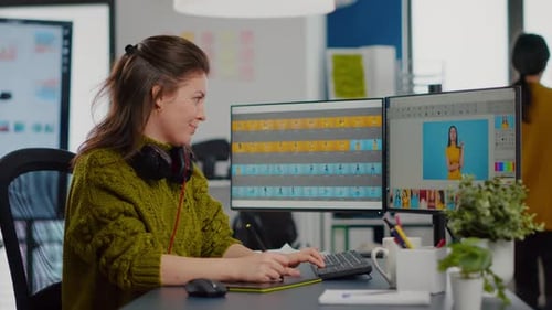 Young Woman Works on Dual Monitors in Office