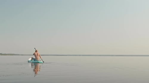 Man Paddleboarding on a Lake on a Sunny Day