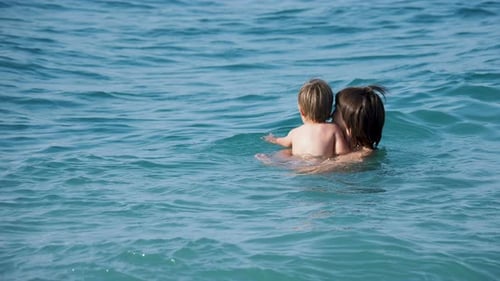 Father with Son Swimming In Sea. Man with Toddler Are Playing in Water Waves. Family Leisure
