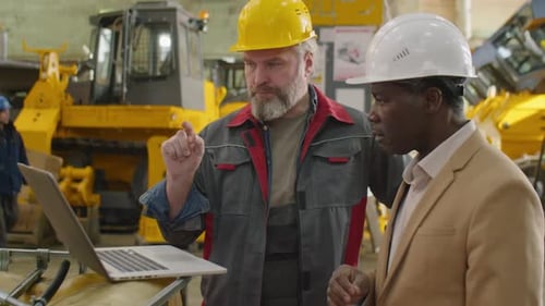 Senior Factory Worker and Engineer Using Laptop and Speaking