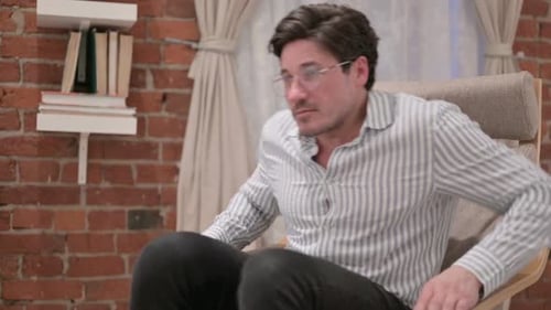 Man Stands Up From Chair in Living Room