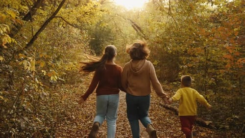 Mom and Children Run Through the Autumn Forest