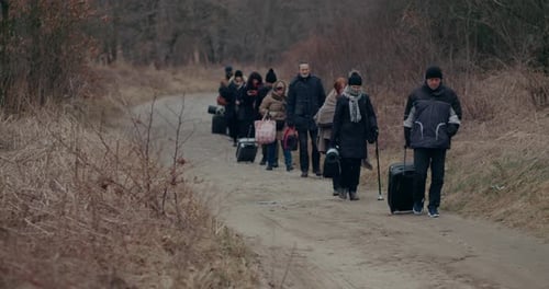 War Immigrants With Luggage Walking On Road During Snowfall