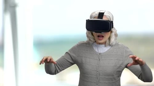 Senior Woman Enjoys Virtual Reality Experience With VR Headset