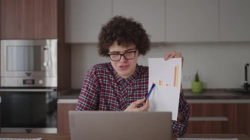 Curly Haired with Glasses Business Man Sitting at Office From Home Desk Looking at Camera and