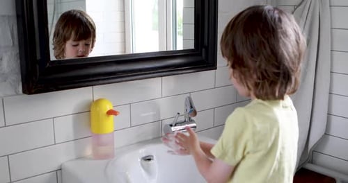 Child Washing Hands in Bright Bathroom