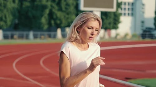 Woman Running on a Track and Field on Sunny Day