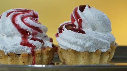 Vierte el sirope de frutos rojos en dos tartas con crema de mantequilla blanca sobre un soporte de metal brillante